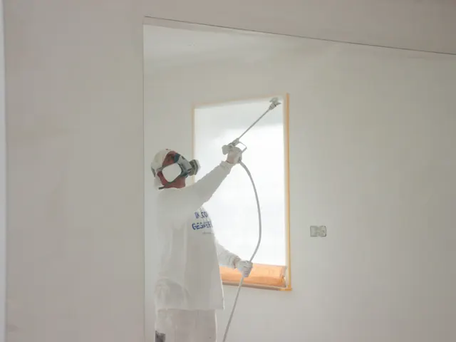 Vakman spuit een gladde muur naast een afgeplakt raam